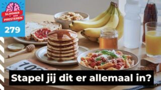 Koolhydraten stapelen: een tafel vol koolhydraatrijk eten voor een wedstrijd, met witte pasta, pannenkoeken met stroop, bananen, brood met jam, honing, jus d'orange, een bidon sportdrank en een startnummer.